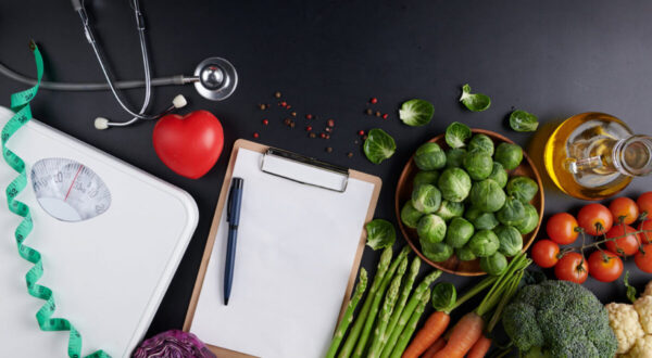 Weight loss scale with centimeter, stethoscope, Dumbbell, Clipboard, pen. Diet concept. Healthy food background. different fruits and vegetables, nuts. concept slimming diet fresh vegetables.
